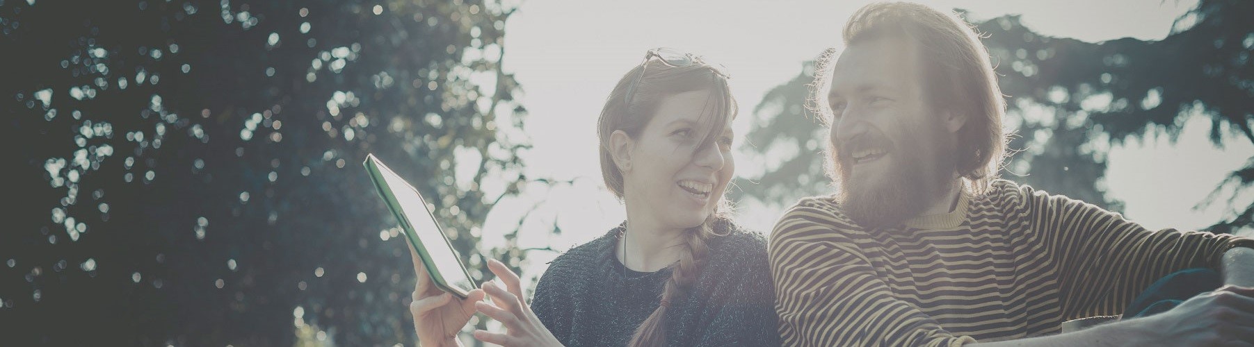 Woman and man smiling and looking at a tablet