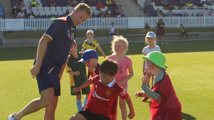 Jets player kicking ball with kids